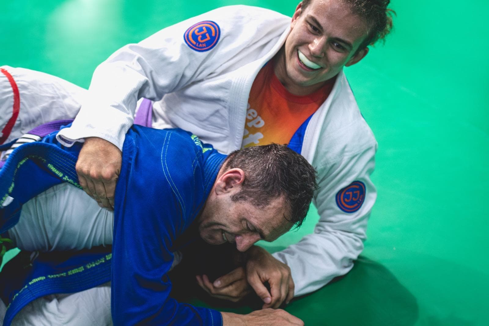 During Brazilian Jiu-Jitsu sparring with bright red athletic tape securely wrapped around injured knee for extra support and visibility.