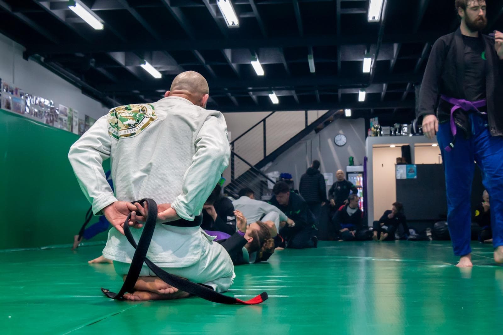 Renegade BJJ student tying their gi belt on the mats